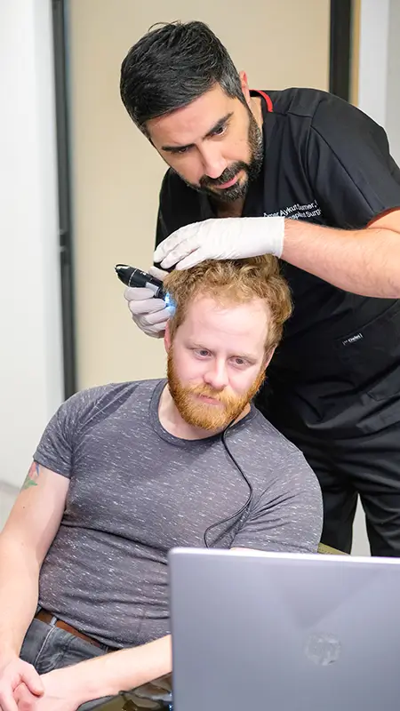 Dr. Aykut examining patient's hair with microscope